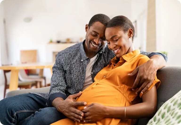 Pregnant couple smiling together on couch